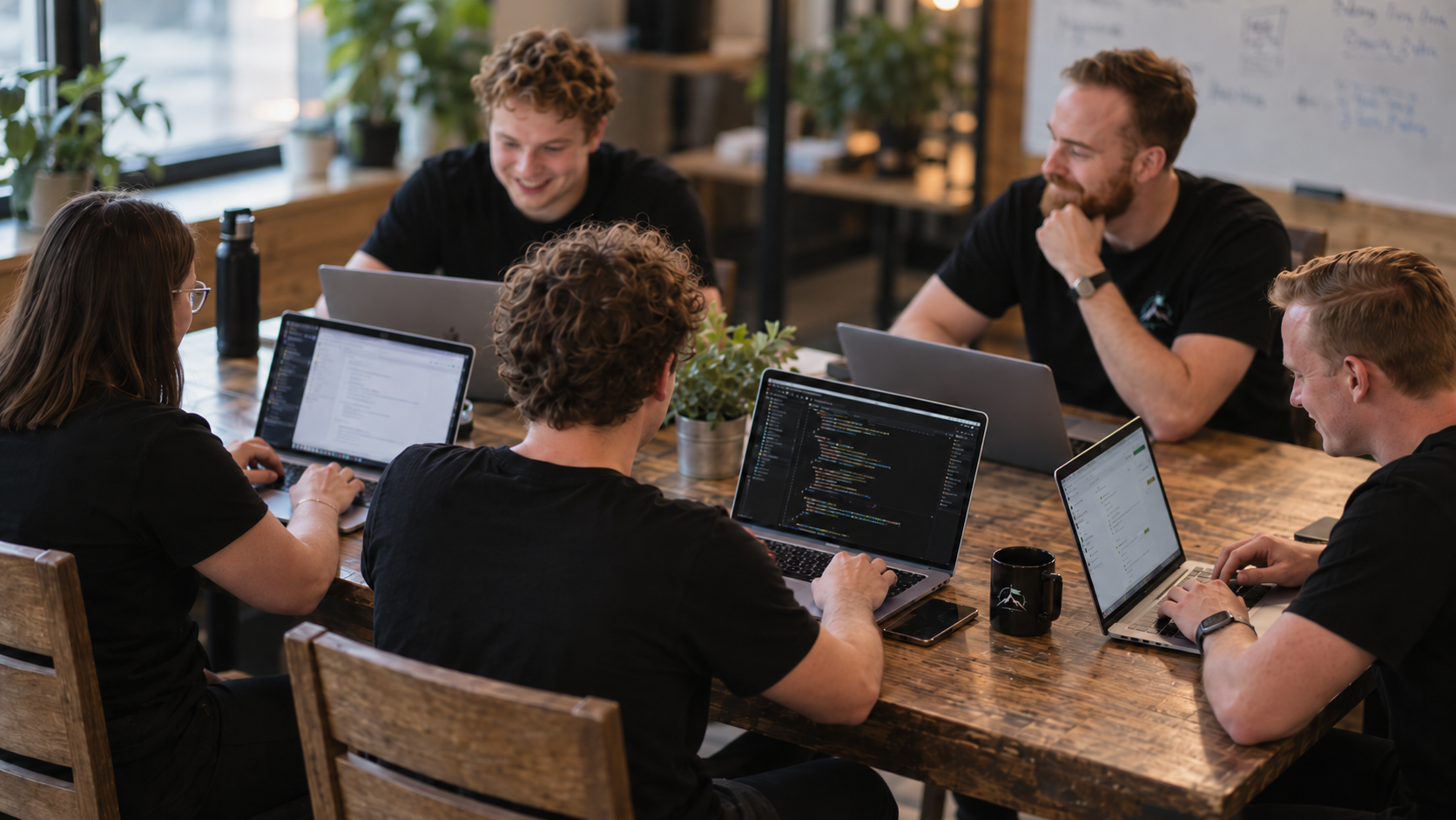 A team working on laptops around a shared table